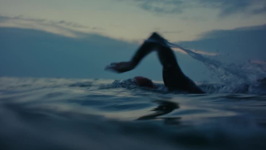 A man swimming inside the sea at sunset
