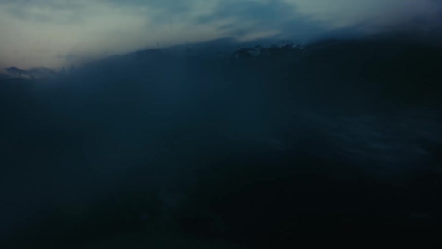 A person swimming on the surface of the sea at dusk