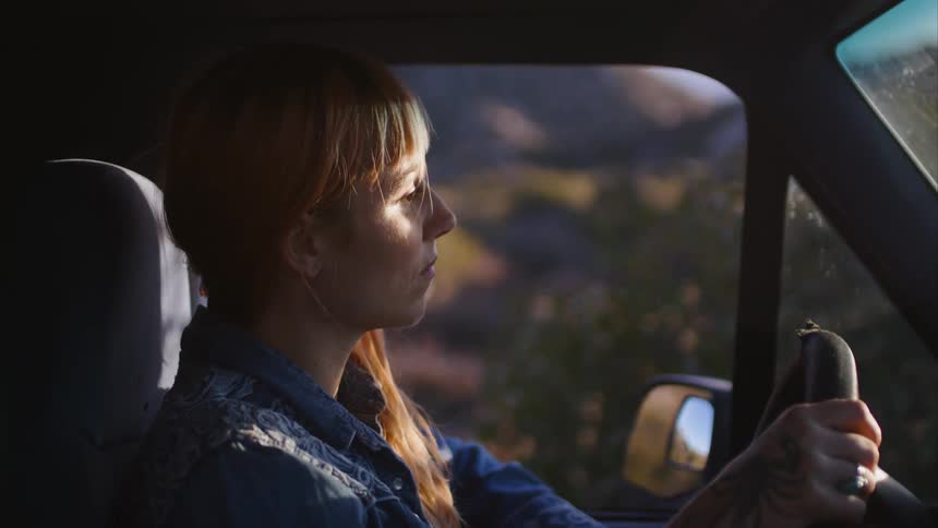 A woman is looking around as she drives her automobile
