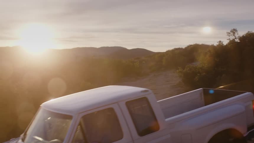 Person driving a pickup truck on a bumpy road at sunset