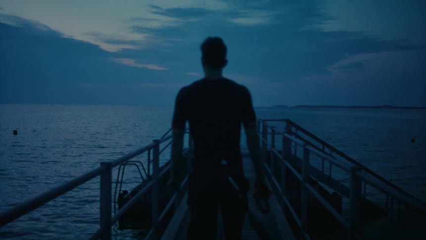 A man walking up the pier as dusk sets in