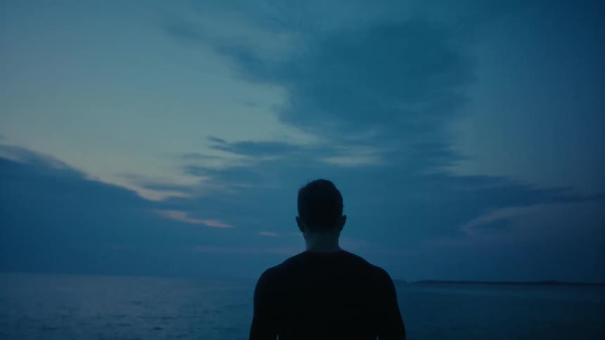 Silhouette of a man walking towards the ocean
