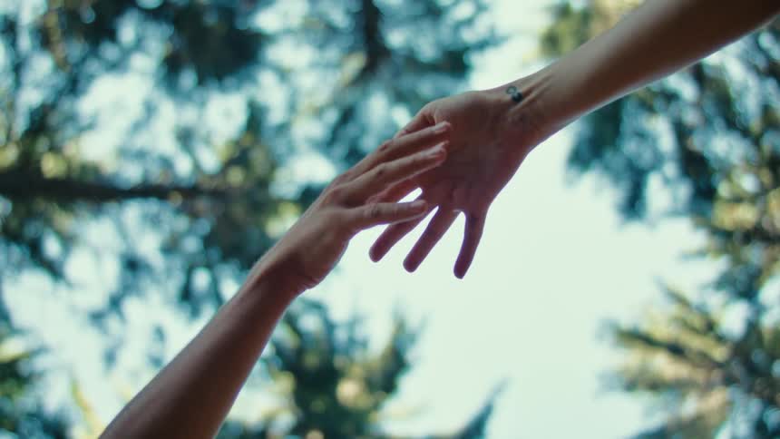 Close up of hands gently touching against a blue sky