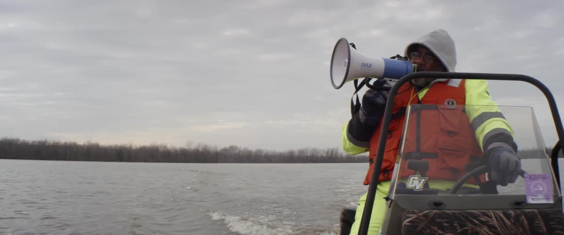 Man using a bullhorn while driving a small boat