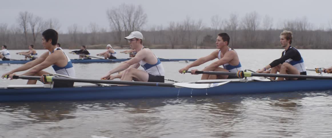 Male rowing teams compete on an overcast day