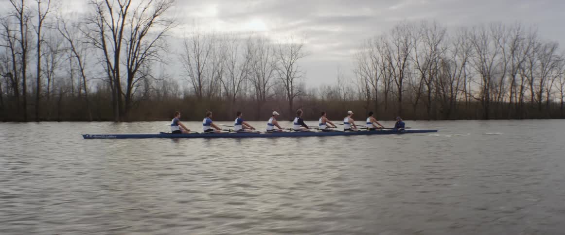A rowing crew rows a boat across the water