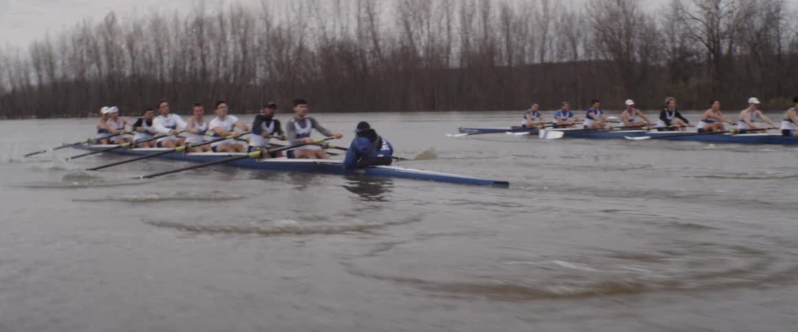 Male rowing teams compete on an overcast day