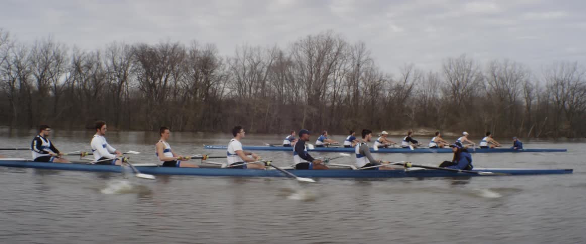 Male rowing teams compete on an overcast day