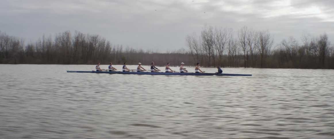 Sculling team moving rapidly across the water on a cloudy fall day