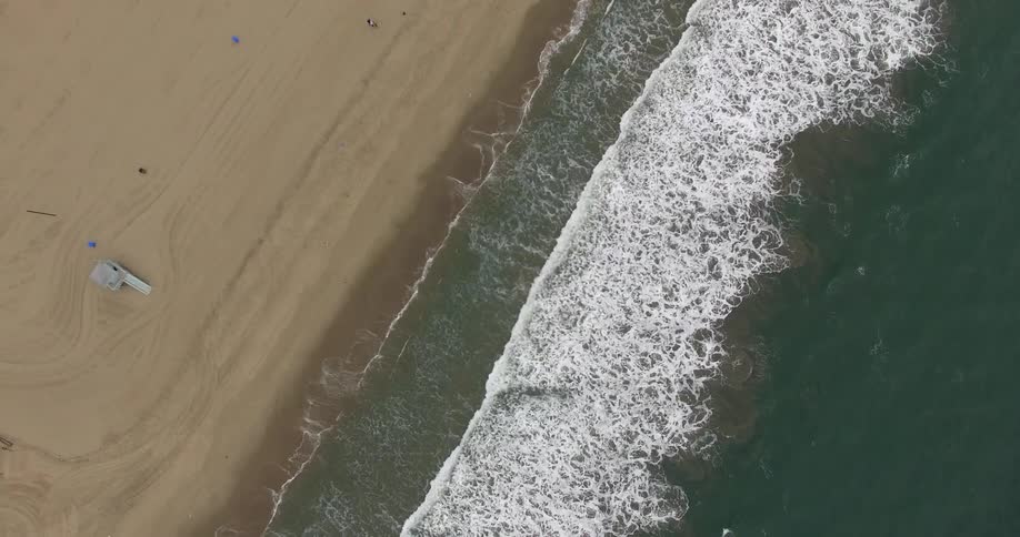 Waves lap the shore of a beach near a lifeguard tower