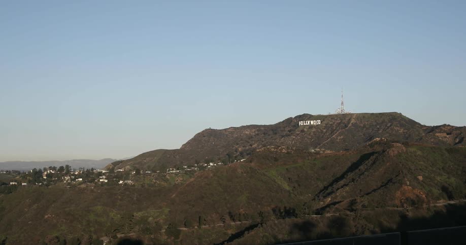 The hollywood sign sits on a hillside under blue skies