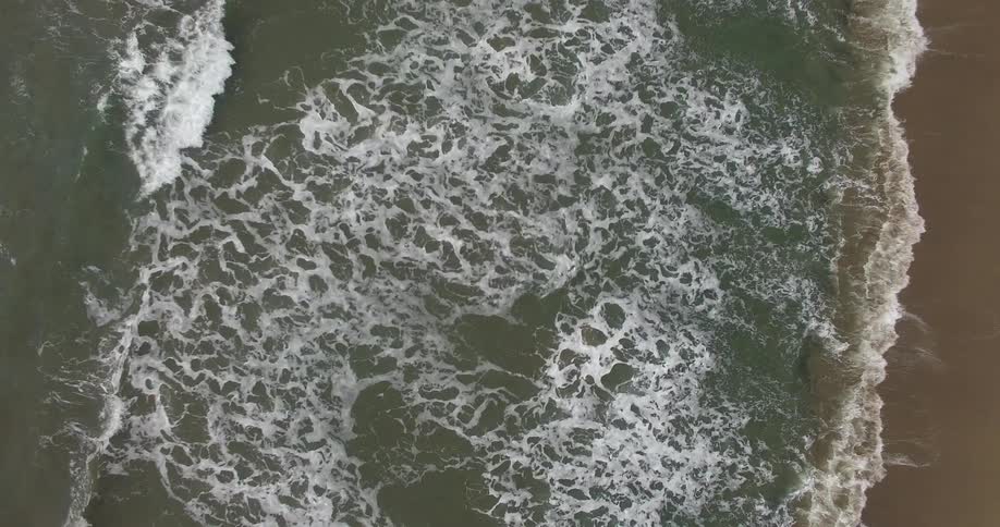 Waves leave lacy traces of foam as they break on shore
