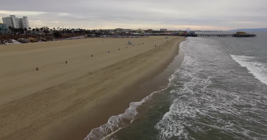 Waves lap the shore of a wide beach on a cloudy day