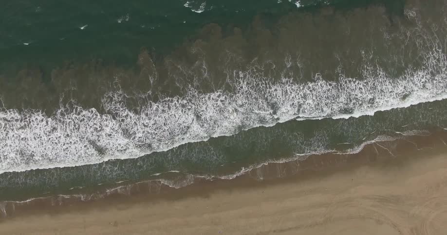 Aerial view of waves crashing against the shore of a beach