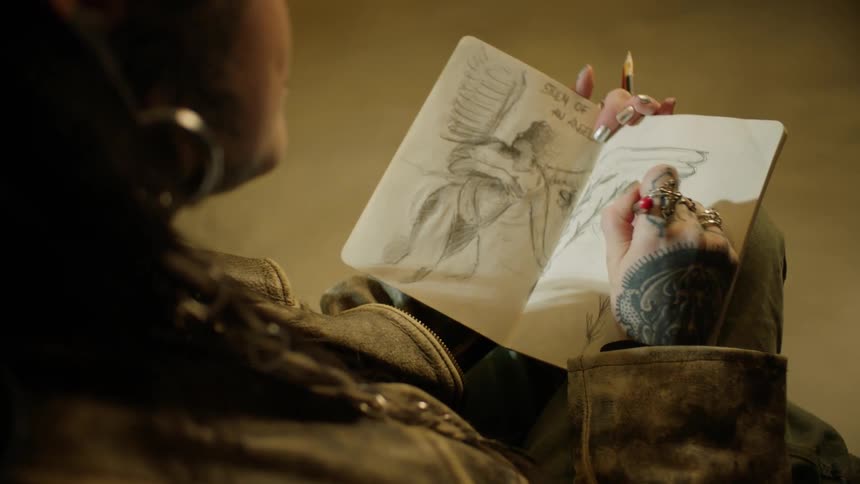 Tattooed artist drawing in her sketchbook