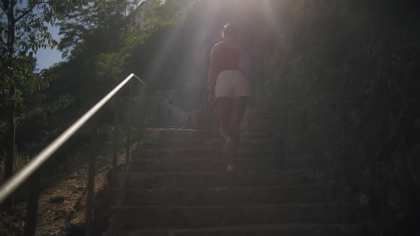A lady climbing stairs in a forest area at daytime