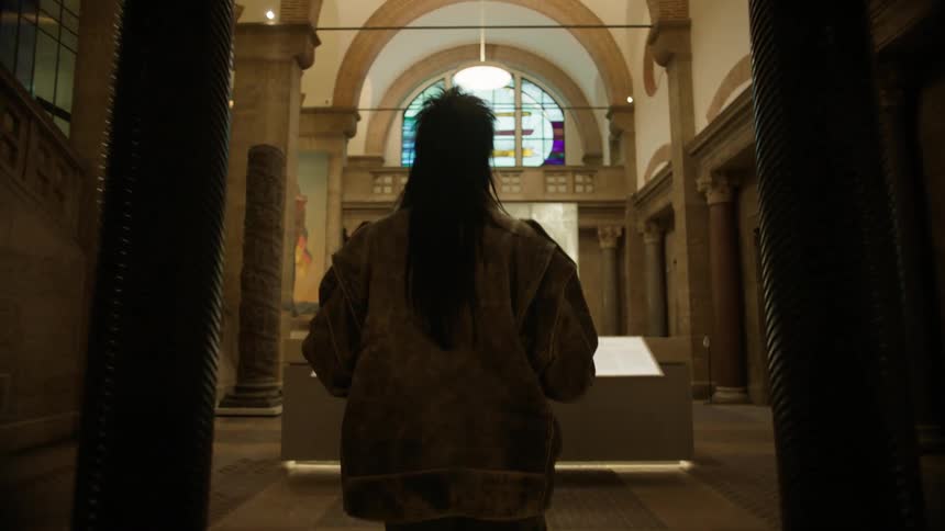 Woman walking with her back turned inside a museum