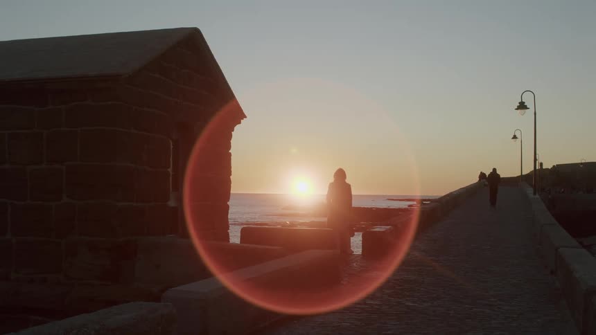View of a boardwalk by the sea with the sunrise and the suns reflection on the horizon on a morning