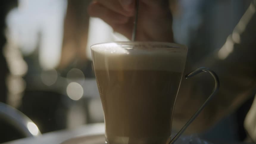 A person is stirring their coffee