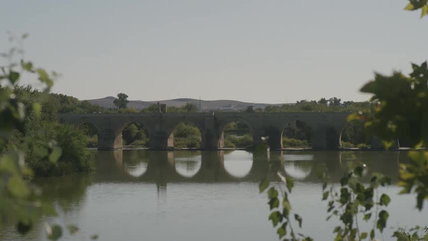 A large bridge that is reflected in a lake below it