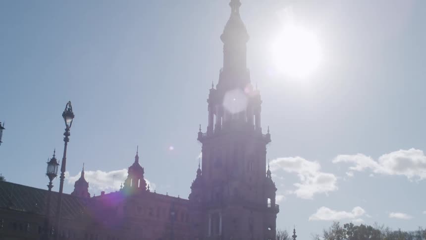 A large tower of ancient architecture and the sun is strong in the sky
