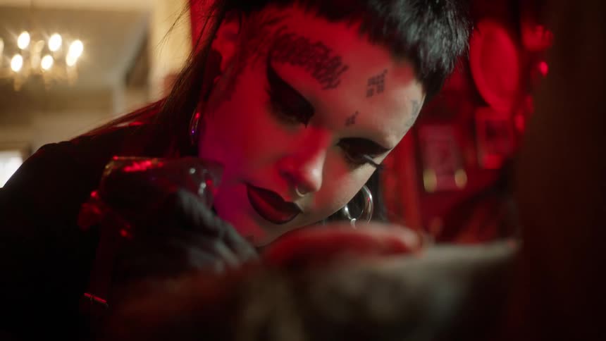Portrait of a young woman tattooing another person