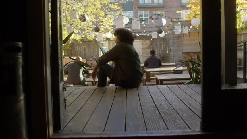 Man sitting on the edge of a wooden sidewalk using a cellphone