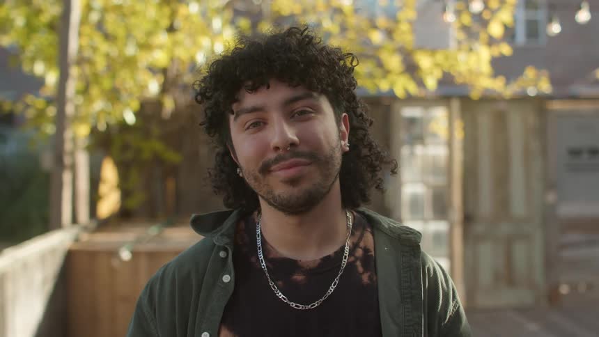 Portrait of a young man giving a gentle smile in an outdoor daylight setting