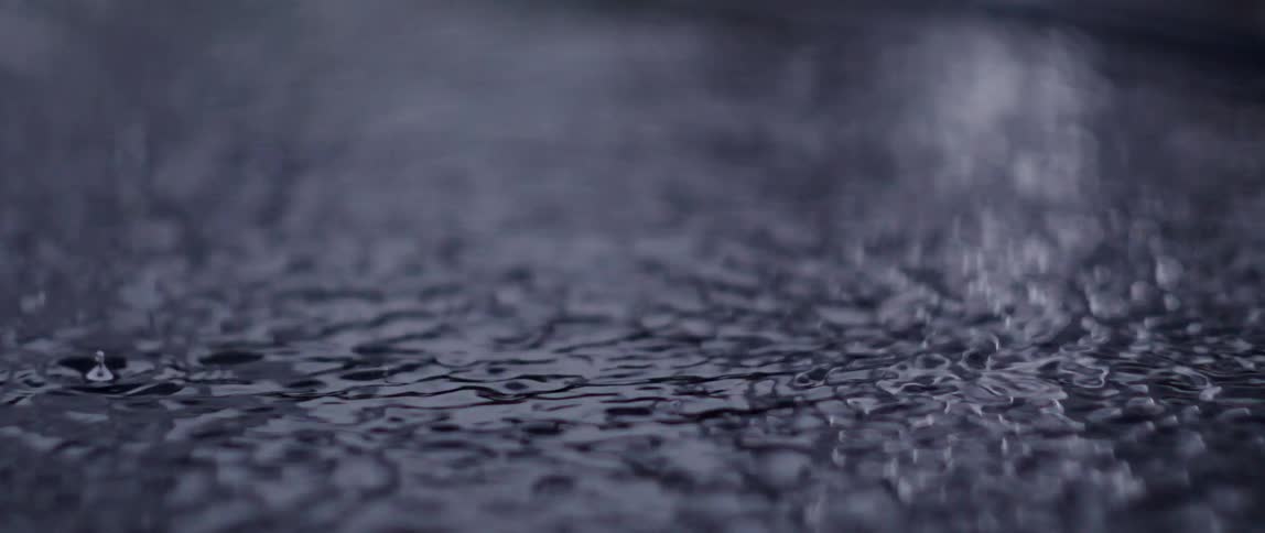 A puddle of water with rain falling making several ripples