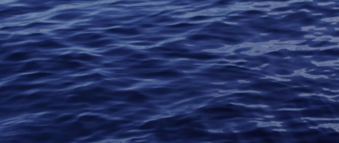 Dark blue ocean waves reflecting minimal light at dawn