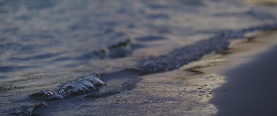 Ocean waves breaking against the beach at sunset