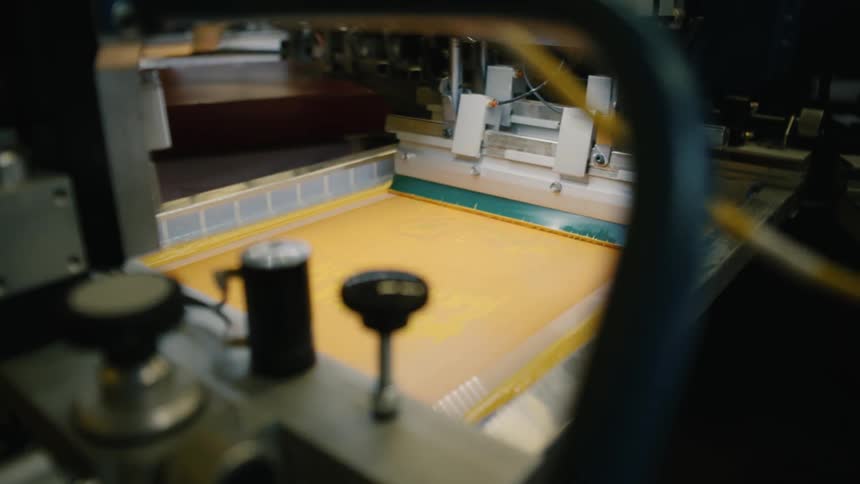 An iron machine is passing over a yellow surface and spreading paint of the same color