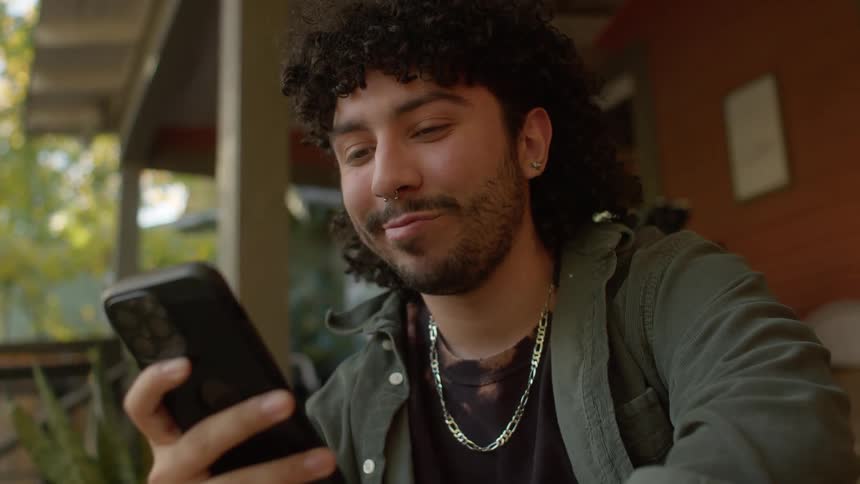 Young man sitting on the porch checks his phone
