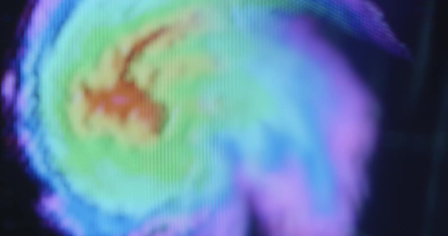 A stressful macro closeup of a television display screening a storm or bad weather pattern animation from the weather forecast or prediction made by meteorologists