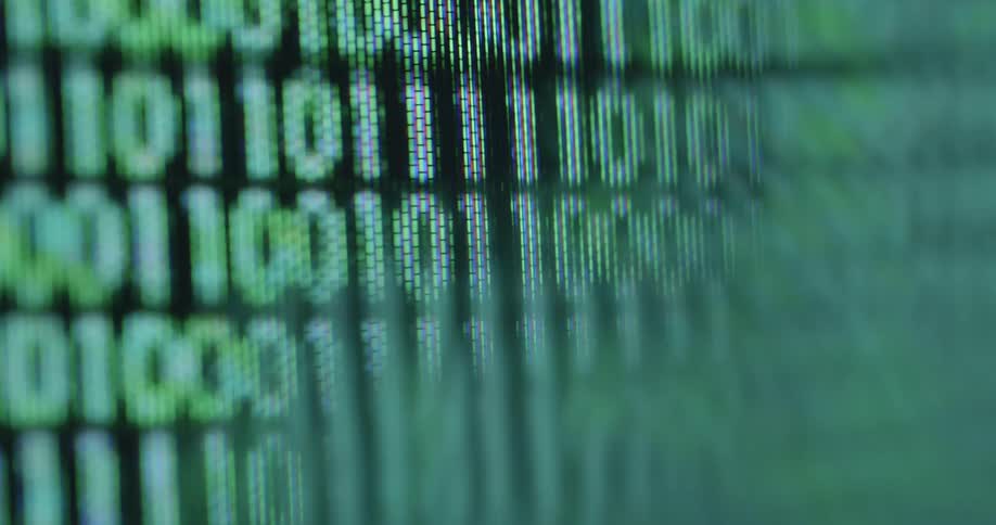 Digitized green ones and zeros fade in and move across the PC screen or display blurring and rippling as a futuristic symbol for computer science or programming and information technology based on the numbers 1 and 0