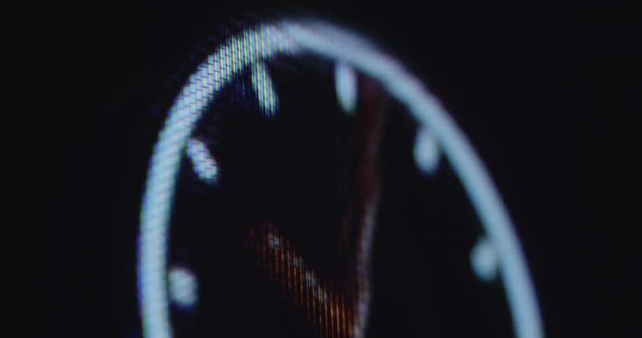 Extreme closeup of a digital wall clock or watch animation on a computer display or television screen that spins faster due to a time lapse as a symbol for the passing of time