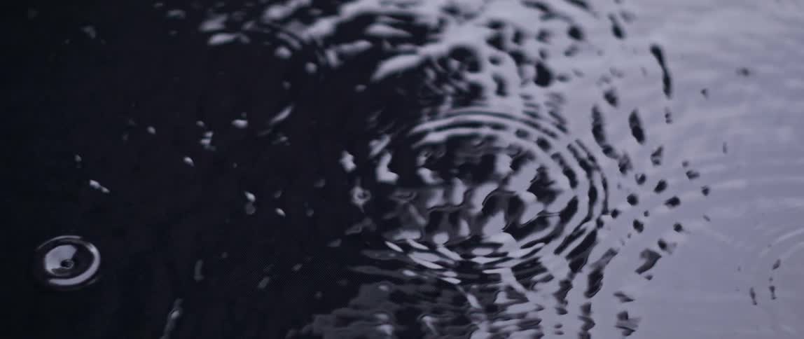 Rippling rings spread as rain falls into the water