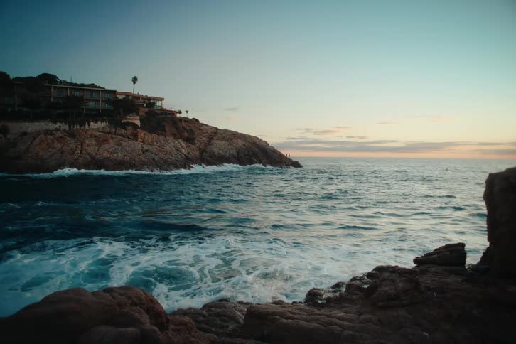 Mansion on a cliff next to the ocean at sunset