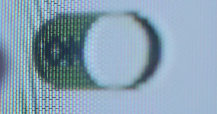 The index finger of an unknown person presses an on and off switch or power button on the touch screen of a display device to activate or deactivate a feature of the operating system or application