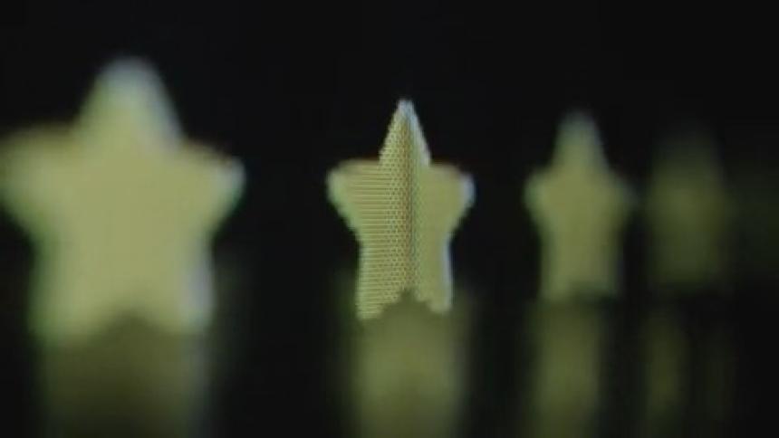 Four or five animated stars pop up on a digital screen with pixelated image symbolizing a positive and great customer review as they appear in front of a black or dark background