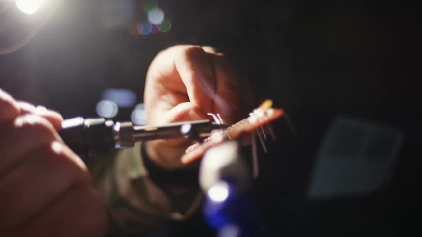 Closeup of a man using a flashlight while soldering in the process of reballing a hardware component