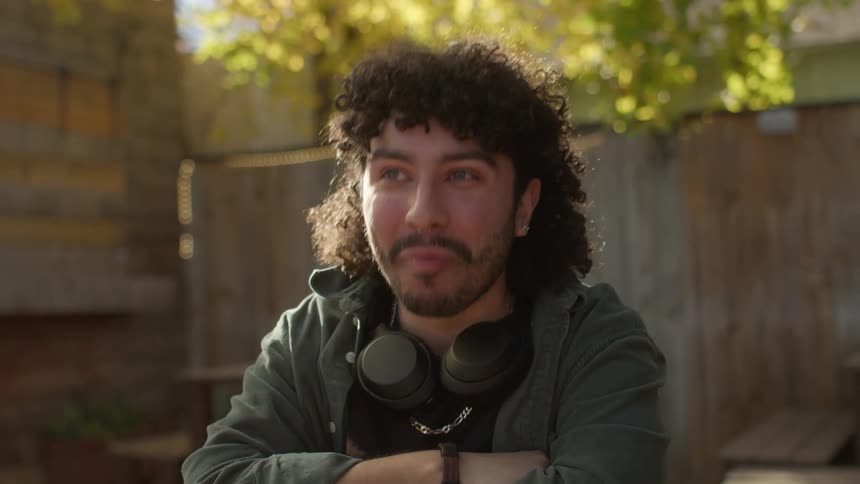 Man sitting with a headset around his neck chatting and smiling in a backyard