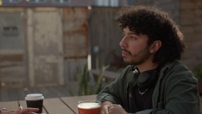 Two friends sitting at table talk with each other in the yard