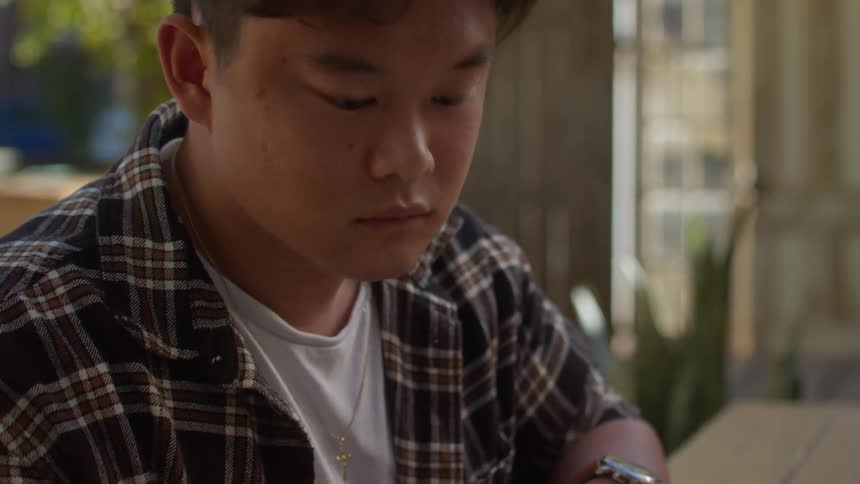 A teenage boy is sitting at a table doing his homework