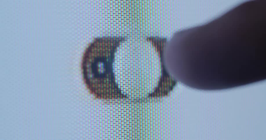 Extreme macro closeup of a pixelated touch screen of a display device with a finger clicking on a digital power green and red button labelled with on and off