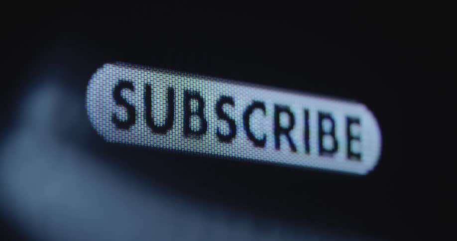 Extreme macro closeup of a mouse cursor clicking on a subscribe button on a dark computer screen with RGB pixels as symbol for a growing amount of newsletter recipients or channel subscribers on an online platform