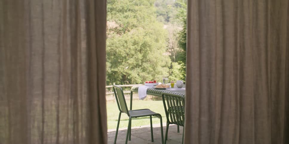 Al fresco dining table framed by curtains