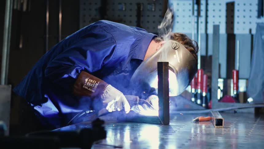 Man wears protective gear while welding metal joint together