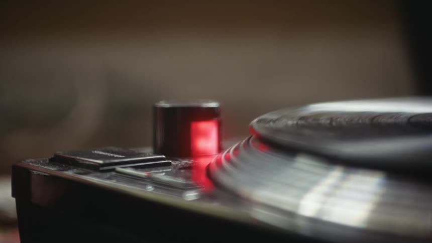 A finger pushes the start button of a turntable and then pushes it off
