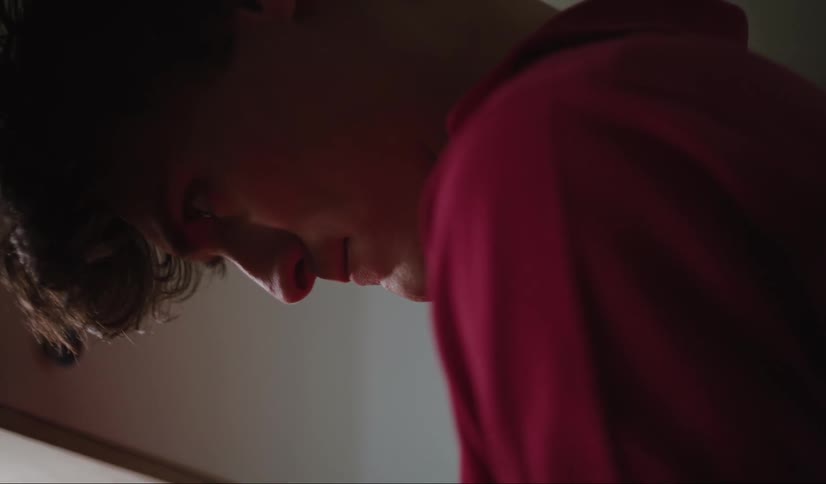 A man wearing a red polo tshirt looks down his attention focused on something below